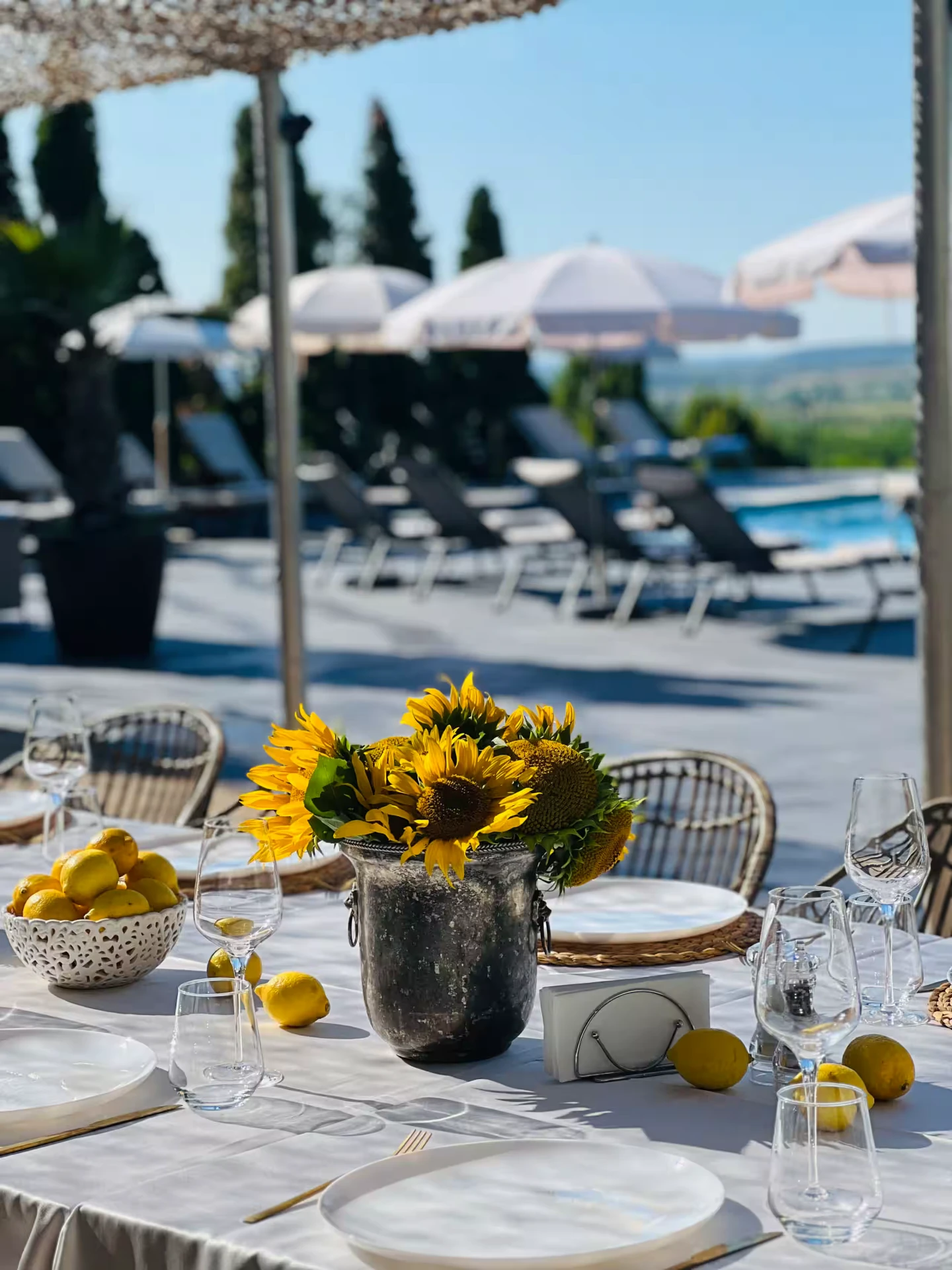 Poolside dining table with sunflowers, lemons and wine glasses